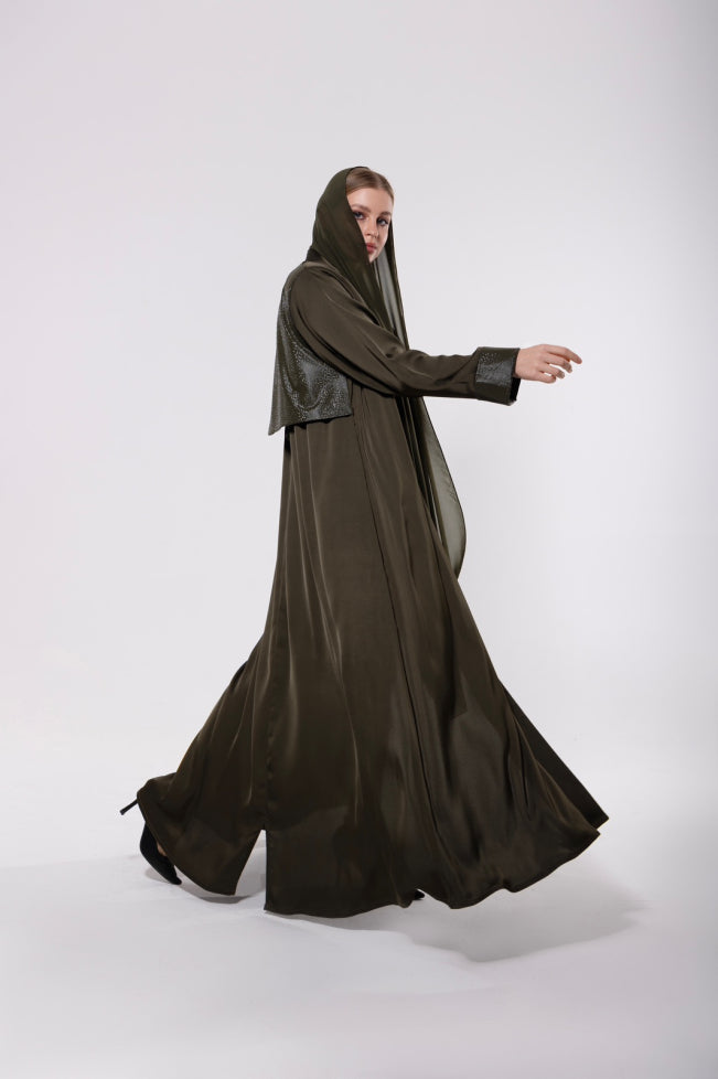 Abaya made from a soft leather and pure silk blend in olive-toned or classic dark hues, featuring a flowing modern cut with a rich, textured finish.