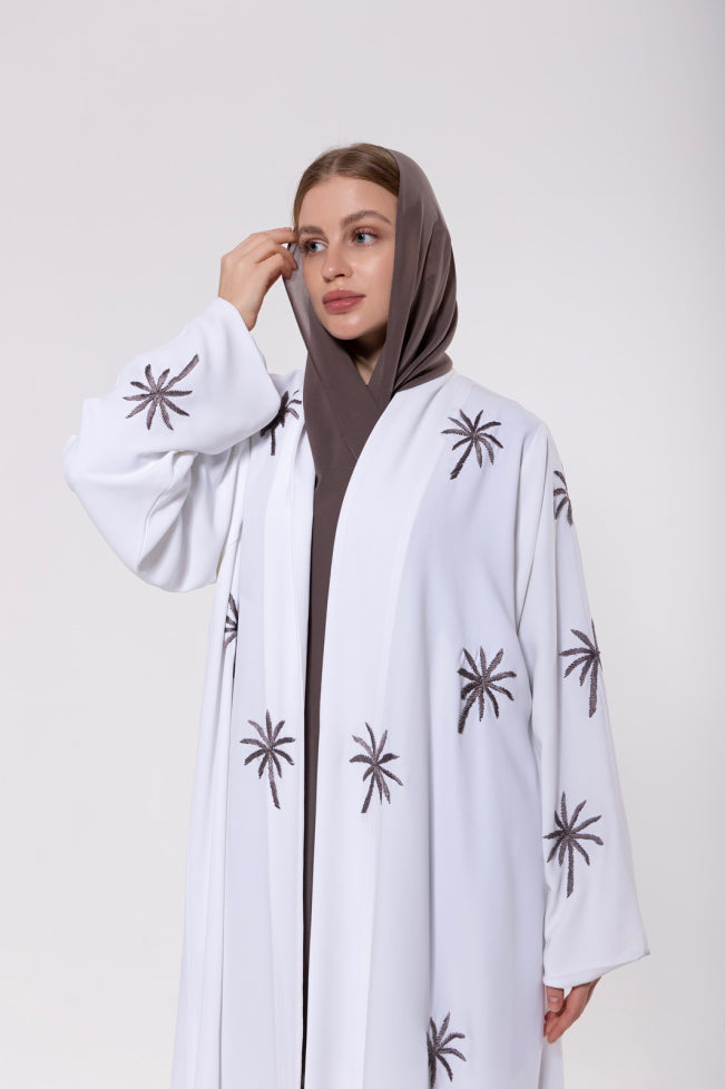 Abaya inspired by the palm trees of Qatar, featuring palm-inspired embroidery on lightweight and elegant fabric.