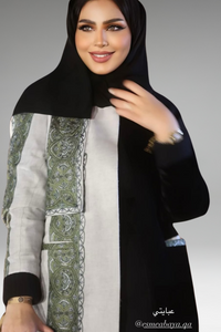Black and beige abaya with green embroidered panel, combining modern sophistication with cultural elegance.