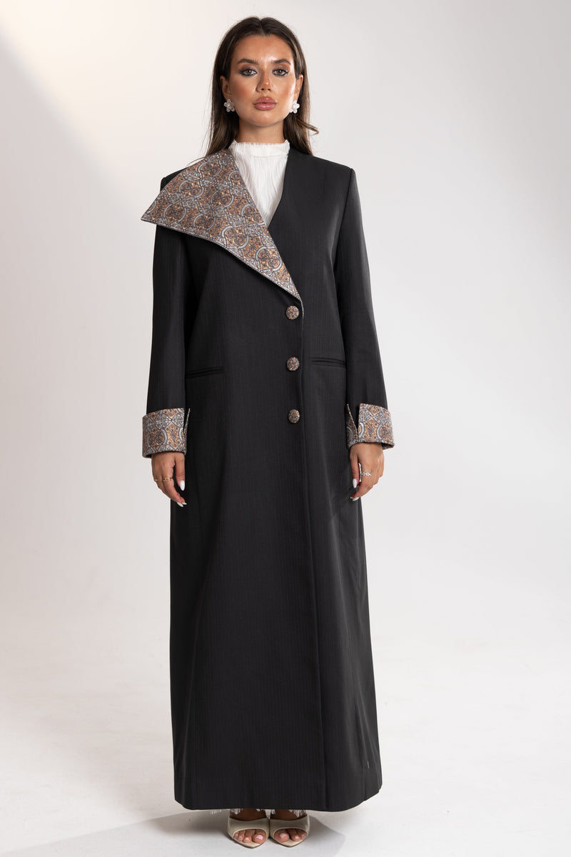 Woman wearing a long gray coat by esme abaya qatar  with embroidery on collar 