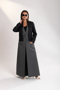 Woman wearing a long black and gray blazer on a white background
