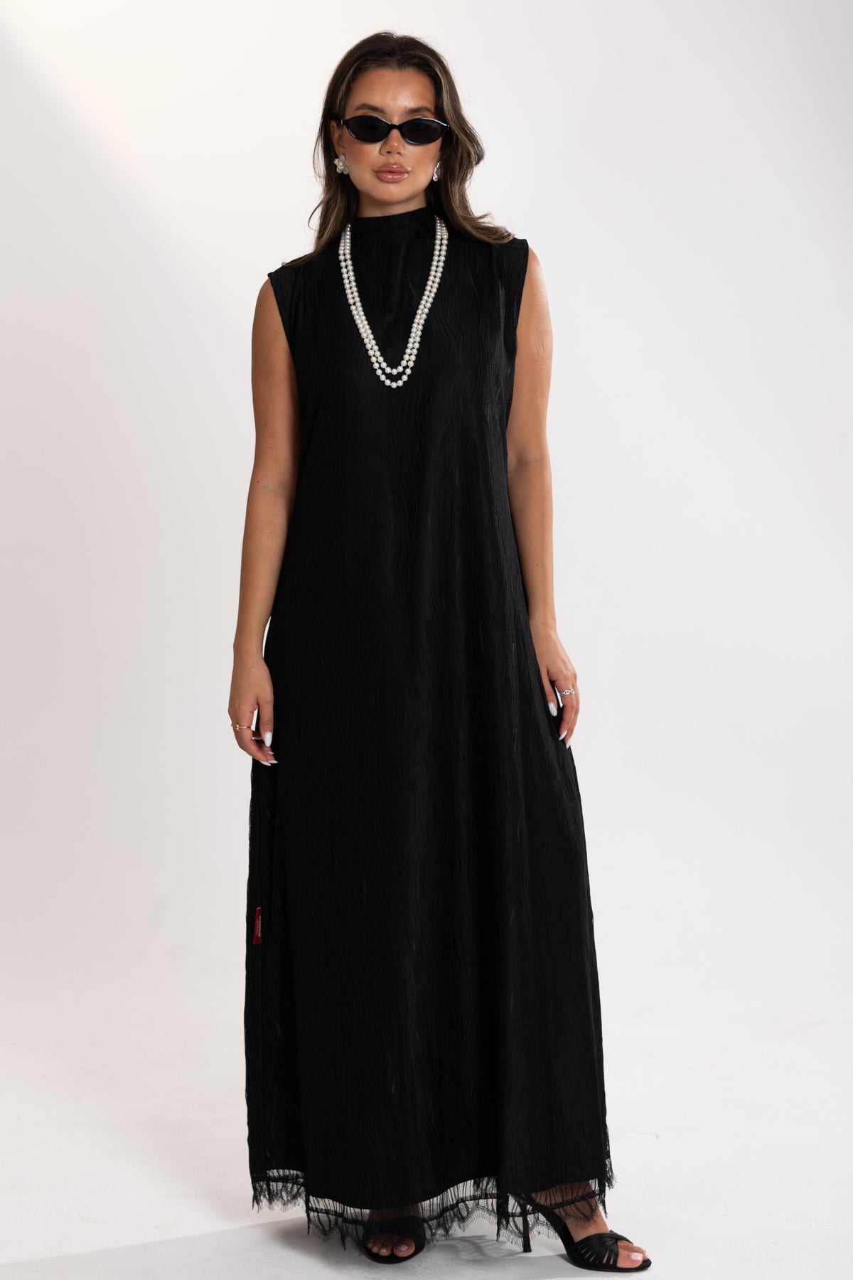Woman wearing a black esme sleeveless dress with lace details on a white background