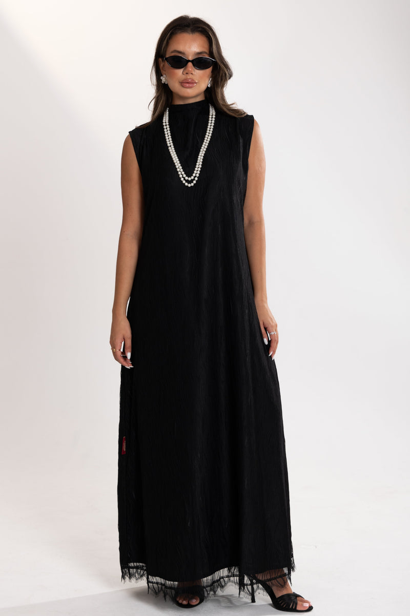 Woman wearing a black esme sleeveless dress with lace details on a white background