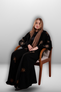 Black abaya with intricate gold embroidery featuring a palm tree motif in golden thread, exuding elegance and luxury.