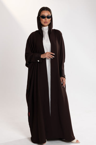 Woman wearing a long brown dress by esme over a white top on a white background