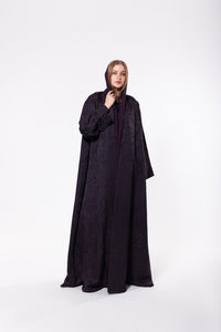 Deep purple abaya made from premium jacquard fabric with a subtle textured pattern, featuring a flowing cut and refined detailing.