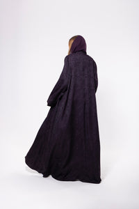 Deep purple abaya made from premium jacquard fabric with a subtle textured pattern, featuring a flowing cut and refined detailing.