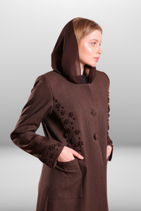 Deep brown coat-style abaya with front buttons, side pockets, and hand-embroidered detailing for a refined and stylish look.