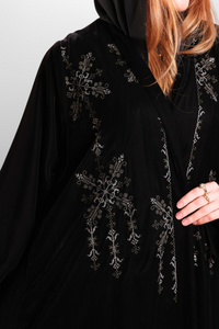 Deep black abaya with intricate embroidered detailing, showcasing luxurious velvet fabric and traditional craftsmanship.