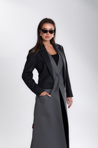 Woman wearing a long black and gray coat on a white background
