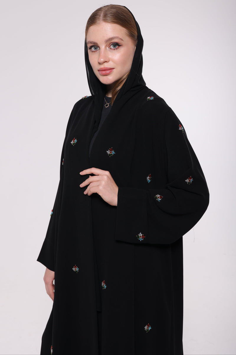 woman wearing a black abaya with beaded embroidery a white background