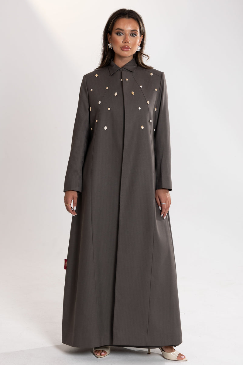 Woman wearing a long gray Esme Abaya showcasing luxury abaya design in Qatar with button details .