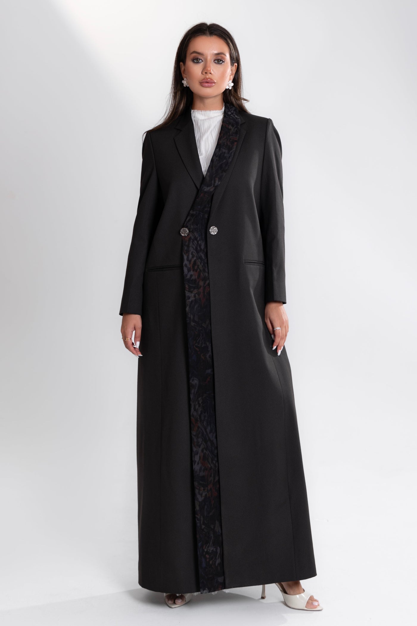 Woman wearing a long black coat by esme on a white background