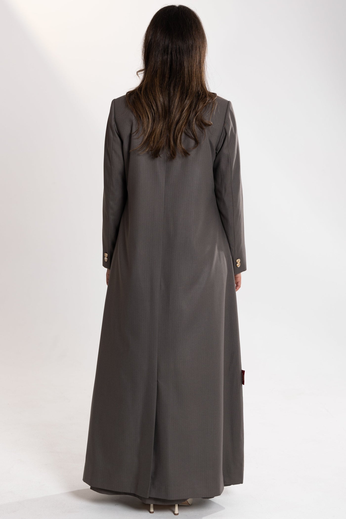 Woman wearing a long gray esme blazer abaya on a white background