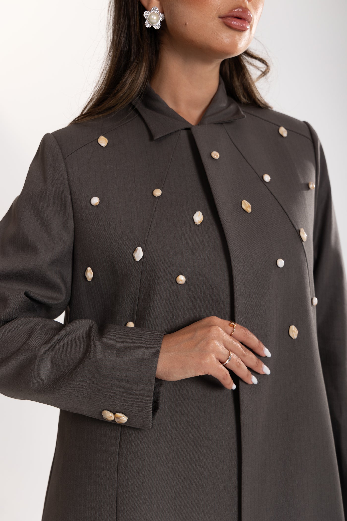 Dark gray esme coat with marble buttons worn by a person on a light gray background