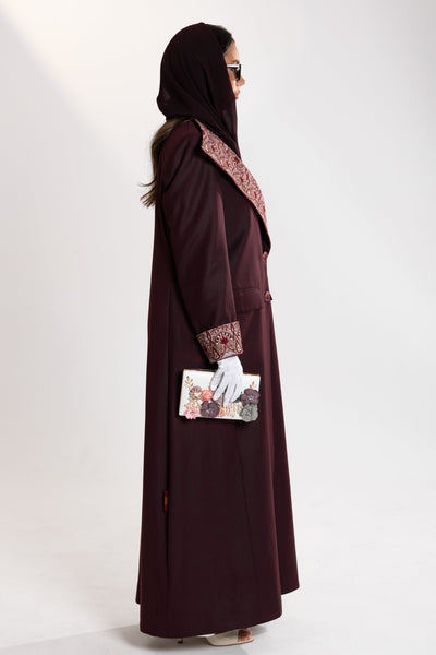 Woman wearing national day abaya by esme qatar and holding a small bag 